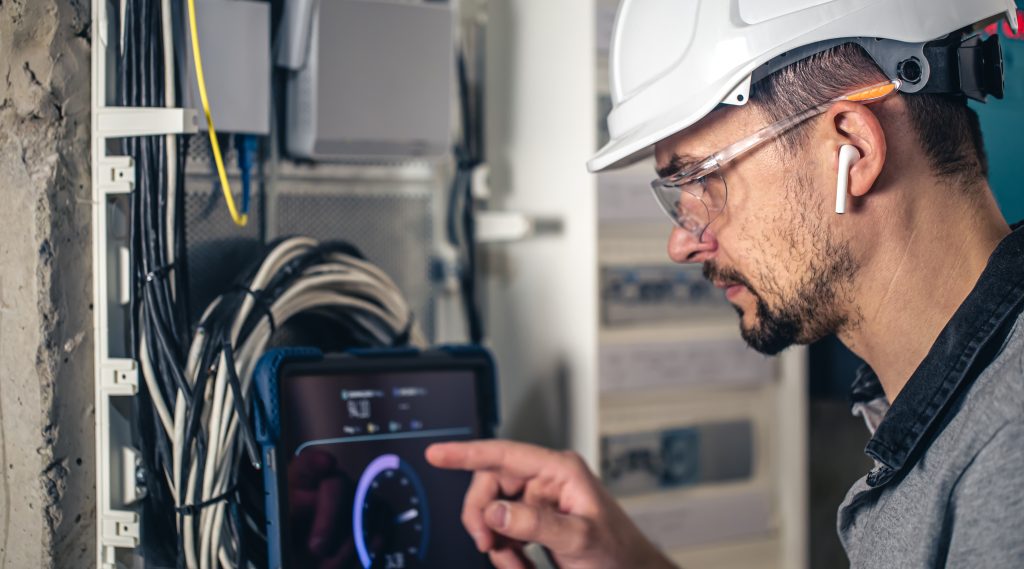 man, an electrical technician working in a switchboard with fuses.